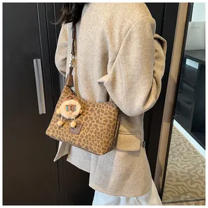 Detail of vintage leopard print shoulder bag featuring a plush lion charm and AJ logo