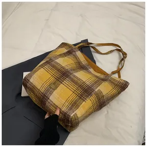 Detail of yellow plaid tote bag showing thick fabric texture and oval metal logo plate