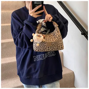 Detail of leopard print handbag with brown leather handle and cute plush charm accessory