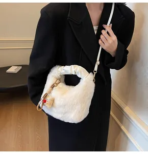 Detail einer weißen Kunstfell-Eimertasche mit Plüsch-Anhänger und abnehmbarem Gurt