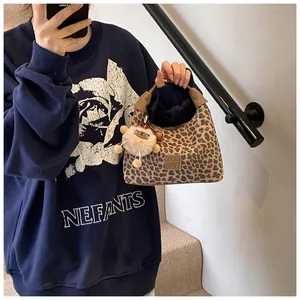 Detail of leopard print handbag with leather logo and plush charm accessory