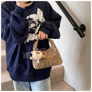 Detail of leopard print handbag with brown handles and a cute plush animal pendant