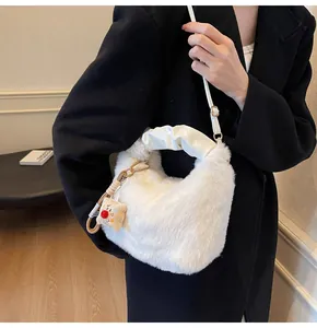 Detail der weißen Kunstpelz-Beuteltasche mit Faltenledergriff und süßem Puppenanhänger