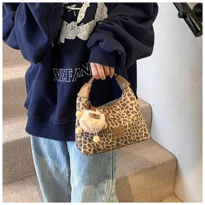 Detail of leopard print tote bag with leather logo patch and plush bear pendant accessory