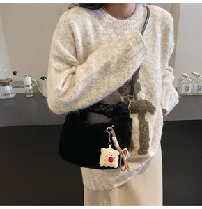 Detail einer Plüschtasche in Schwarz mit Toast-Anhänger und Schultergurt aus Leder
