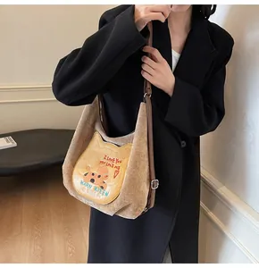 Détail du sac cabas en velours côtelé kaki avec écusson de chien et sangle en cuir brun
