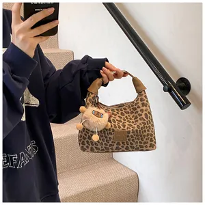 Detail of leopard print suede handbag with brown leather handle and cute plush charm
