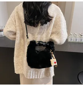 Detail der schwarzen flauschigen Eimertasche mit Plüsch-Anhänger und Goldbeschlägen