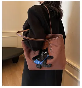 Detail of a brown suede tote bag featuring a cute black cat embroidery and leather handles