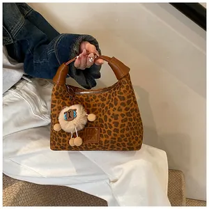 Close-up of leopard print faux suede handbag with leather handle and plush doll charm