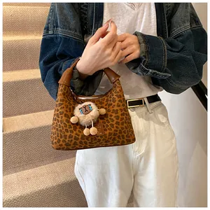 Detail shot of leopard print handbag with plush sheep charm decoration on stairs