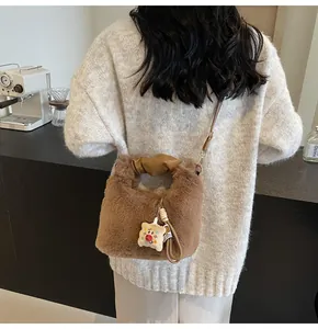 Detail der braunen Plüschtasche mit süßem Anhänger und ledernem Tragegriff