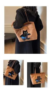 Close-up of brown tote bag featuring 3D black cat embroidery with a blue fish accessory