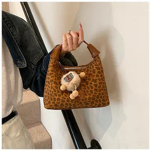 Close-up of leopard print hobo bag with brown leather strap and white alpaca charm