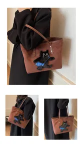 Detail of a brown suede tote bag with a unique 3D black cat embroidery and blue fish detail