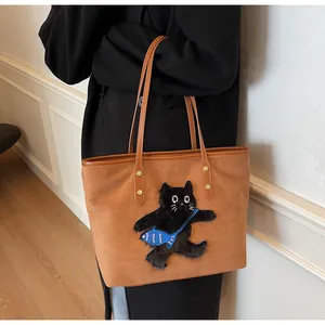 Detail of a brown suede tote bag featuring a cute black cat patch and leather straps
