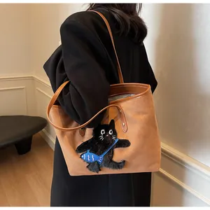 Detail of brown tote bag featuring unique black cat embroidery and blue fish accent