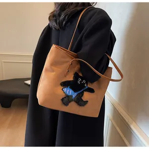 Detailed embroidery of a black cat with a blue fish bag on a brown tote backpack