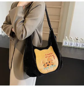 Détail du cabas en velours noir avec écusson de chat jaune et broderie colorée