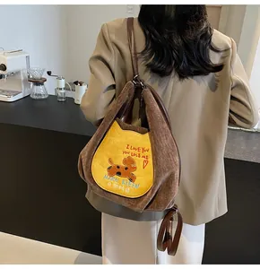 Détail de broderie de chien et texte sur sac à dos convertible en velours côtelé marron