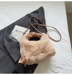 Draufsicht auf flauschige beige Beuteltasche mit braunem Faltenhenkel und langem Gurt