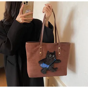 Close-up of brown suede tote bag with 3D plush cat embroidery and gold rivet details