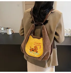 Détail d'un sac à dos en velours côtelé marron avec poche chat jaune et cuir