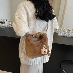Braune flauschige Eimertasche mit gerafftem Kunstledergriff und gelbem Plüsch-Anhänger