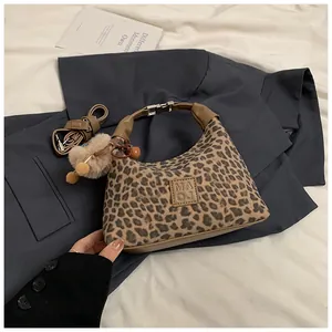 Detail of leopard print hobo bag with plush ball charm and silver metal buckle