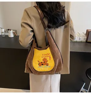 Détail d'un grand sac cabas en velours côtelé marron avec écusson chat jaune brodé