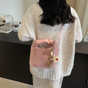 Rosa Plüsch-Eimertasche mit flauschiger Textur und süßem Anhänger in gemütlichem Ambiente