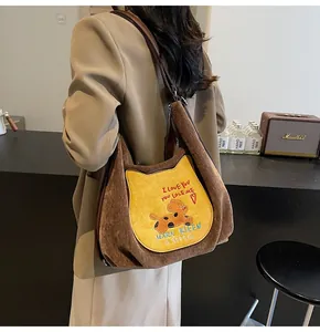 Détail d'un sac cabas en velours côtelé marron avec une poche brodée en forme de chat