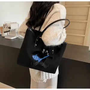 Detail of black tote bag featuring a 3D plush cat embroidery and blue fish charm