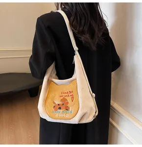 Détail du cabas beige montrant l'écusson chat jaune avec broderie et texture douce