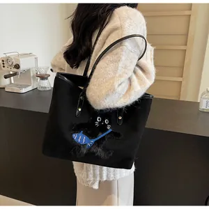 Detail of a black canvas tote featuring a plush cat patch with a blue fish bag charm