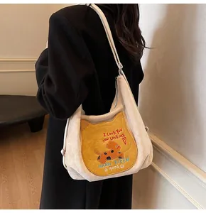 Détail du sac fourre-tout en toile beige avec broderie chat jaune et bandoulière réglable