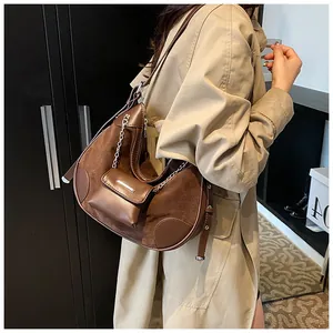 Detail of a brown crescent shoulder bag featuring suede texture and silver metal chain