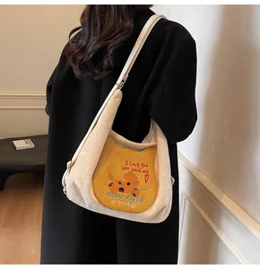 Détail d'un sac cabas en velours côtelé beige avec écusson de chat jaune et bandoulière