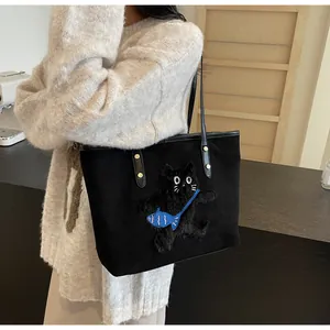 Detail of black tote bag featuring a fuzzy cat patch and blue fish charm accessory