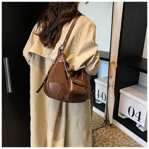 Detail of a brown suede hobo bag with adjustable strap and mini coin purse attachment