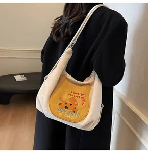 Détail du sac à bandoulière en toile avec poche jaune et broderies colorées