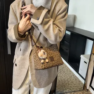 Retro leopard print faux suede shoulder bag with plush charm on a model in brown blazer