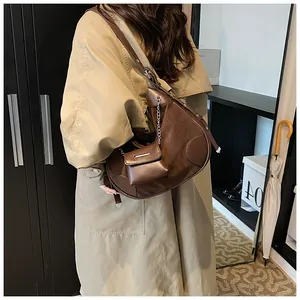 Detail of a brown half-moon crossbody bag with suede patchwork and metal chain