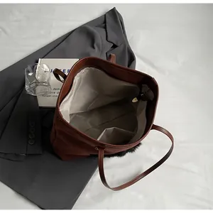 Detail view of large brown tote bag interior with gray lining and stylish plush trim