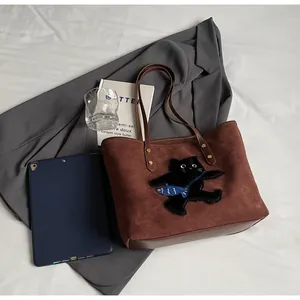Detailed close-up of brown suede tote bag with cat embroidery and blue fish accent