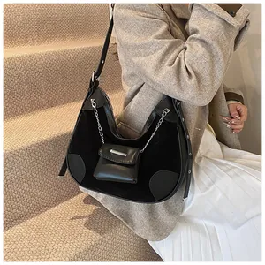 Detail of black crescent shoulder bag featuring suede patchwork and silver chain coin pouch