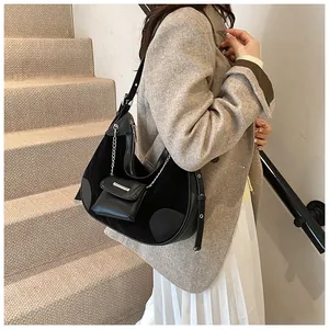 Detail of black hobo bag featuring suede patchwork, silver chain, and mini pouch accessory