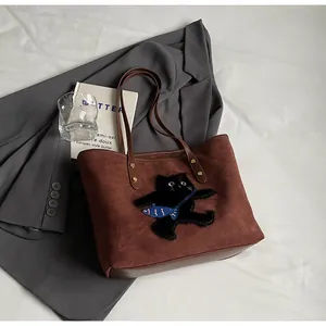 Detail of a brown tote bag featuring a cute black cat embroidery and soft suede texture