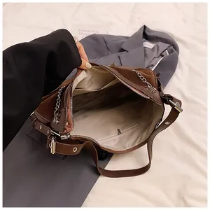 Detail of dark brown tote bag showing suede texture, metal chain, and internal pockets