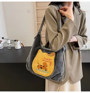 Détail du grand sac cabas gris en velours avec écusson de chat jaune et bandoulière cuir